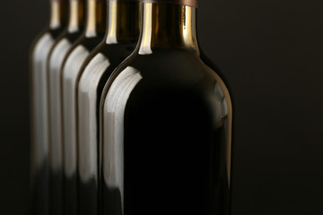 Wine bottles in a row on dark background, close up