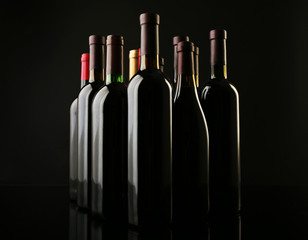 Wine bottles in a row on black  background, close up
