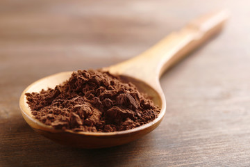 Wooden spoon with cocoa powder on the table, close-up
