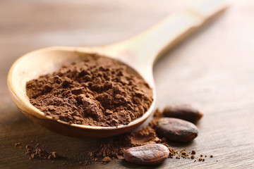 Wooden spoon with cocoa powder on the table, close-up