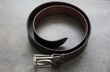 Leather belt with buckle on gray background