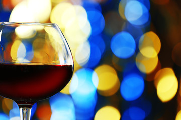 A glass of red wine on blurred lighted background