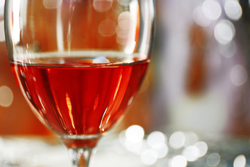 A glass of pink wine on blurred lighted background