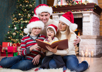 Cheerful family of four reading together on Christmas evening