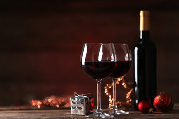 Red wine and Christmas ornaments on wooden table on wooden background