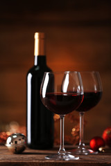 Red wine and Christmas ornaments on wooden table on wooden background