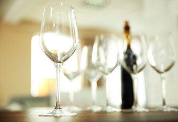 Empty wine glasses with bottle on wooden table against blurred background