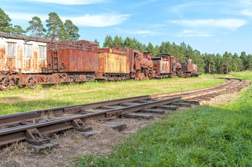 Fototapeta na wymiar Old rusty waggonage with steam locomotive, carriage and wagon with railway before. Talitsy, Yaroslavsky region, Russia. 