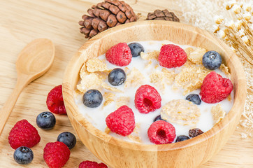 Bowl of cereals with raspberries and blueberrys on a wooden tabl