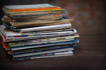 Pile of old books on wooden table against brick wall, close up