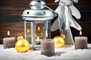 Grey lamp, fir tree, candles and baubles in a snow over wooden background, close up