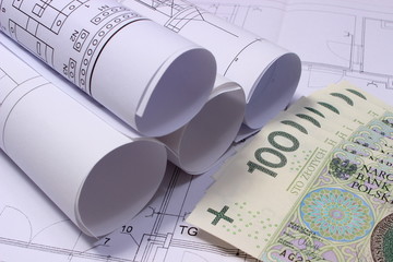 Rolls of electrical diagrams on construction drawing of house and money