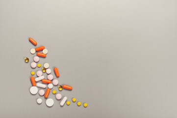 Spilling pills and capsules on a gray background