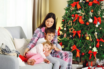 Mother with daughter and son near Christmas tree