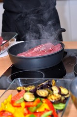 Raw meat prepares on a frying pan