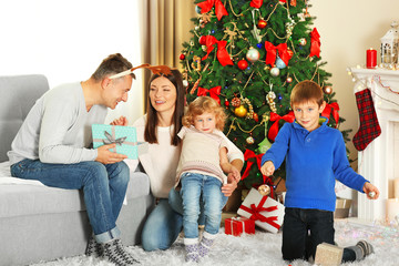 Happy family with gift boxes in home holiday living room, at morning