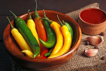 Chili peppers, homemade hot sauce and spices on sackcloth, on wooden background