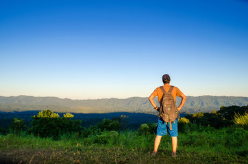 Fototapeta premium An adventurous traveler viewing top rocky mountain & valley during sunset time