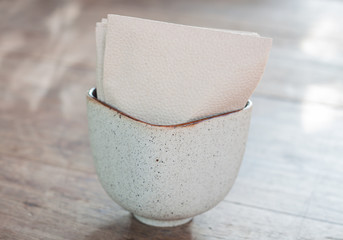 Tissue paper in ceramic cup on wooden table