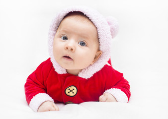 Happy baby lying on tummy wearing a red and white Christmas Santa suit.