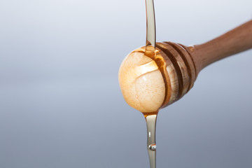 honey dipper with honey pouring in on white background