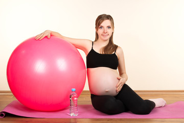 Fototapeta na wymiar pregnant woman sitting on yoga Mat near exercise ball on white background