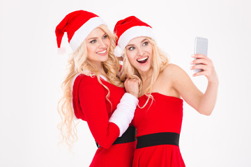 Cheerful blonde sisters twins making selfie using cell phone