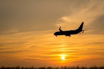 Airplane is flying towards the runway from the airport. Photo taken during a beautiful sunset.