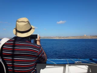 Foto op Canvas Турист, фотографирующий приближающийся остров с палубы корабля в летний солнечный день © keleny