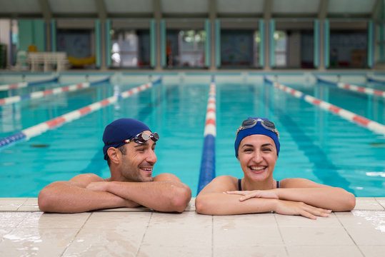 Young couple of swimmers inside swimming pool.