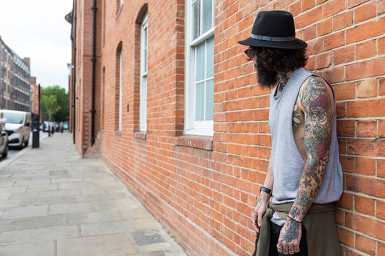 Young tattooed man portrait against brick wall in Shoreditch bor