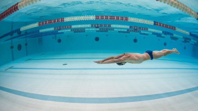 Professional man swimmer inside swimming pool. Underwater image.