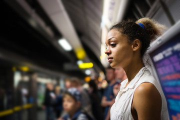 Young woman portrait inside underground in London waiting for train. - obrazy, fototapety, plakaty