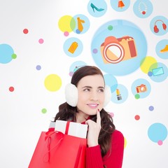 Composite image of brunette with ear muffs holding shopping bag 
