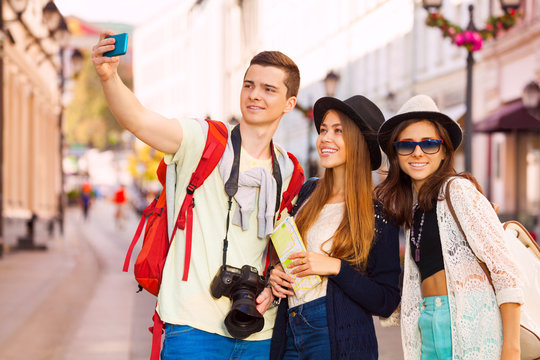 Girls and guy taking selfies with mobile phone