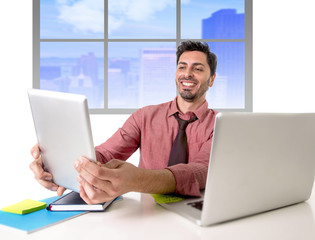 businessman working at office desk using digital tablet pad smiling happy sitting in front of computer laptop looking satisfied