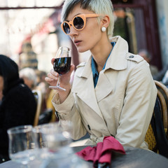 Young woman drinking a glass of wine in a cafe in Paris, France.