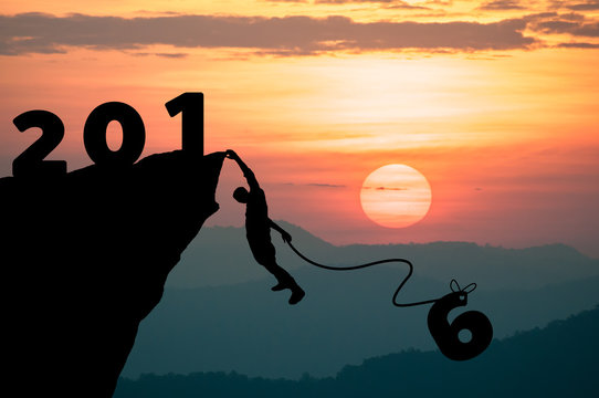 Silhouette Man climbs into cliff to make the word the New Year 2016.