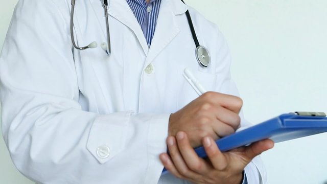 medico con stetoscopio, camice e cartellina che scrive su cartellina la diagnosi dopo un'analisi