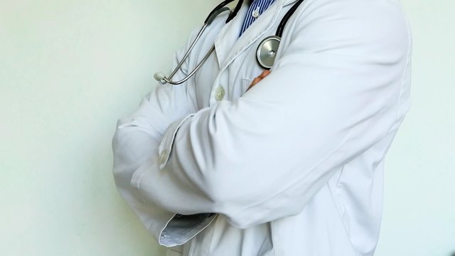 medico con stetoscopio e camice incrocia le braccia