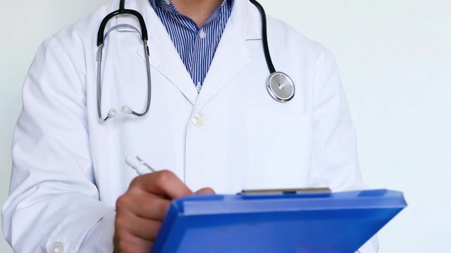 medico in ospedale con stetoscopio, camice e cartellina che scrive cura per paziente malato