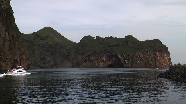 boat passing rocks at westman islands in iceland