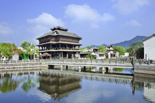 Ancient wooden house and bridge reflected in a tranquil canal, Hengdian, China