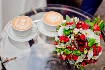 Coffee and bouquet of red and white flowers.