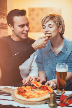 Young couple sitting at the table and eating pizza
