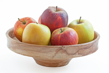 Pommes de différentes couleurs dans une corbeille sur fond blanc