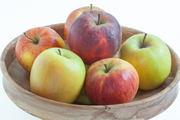 Fototapeta na wymiar Pommes de différentes couleurs dans une corbeille sur fond blanc