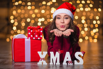Pretty female sending kiss and lying over glittering background