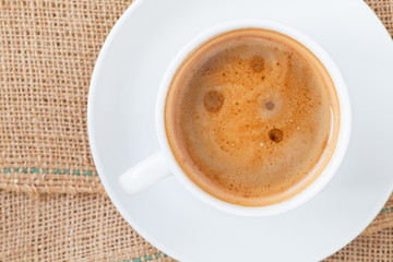 Cup of hot coffee on brown fabric