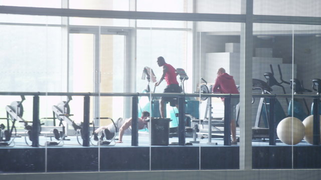  Long shot of group of men and one woman working out in the gym
